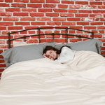 woman laying in bed featuring pewter organic flannel pillowcases and chalk organic flannel Duvet cover
