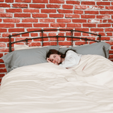 woman laying in bed featuring pewter organic flannel pillowcases and chalk organic flannel Duvet cover