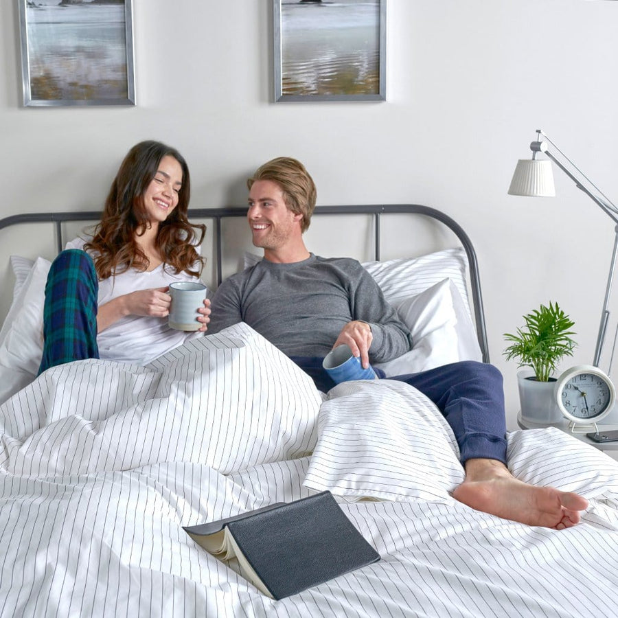 Man and Woman laying under charcoal stripe duvet cover 