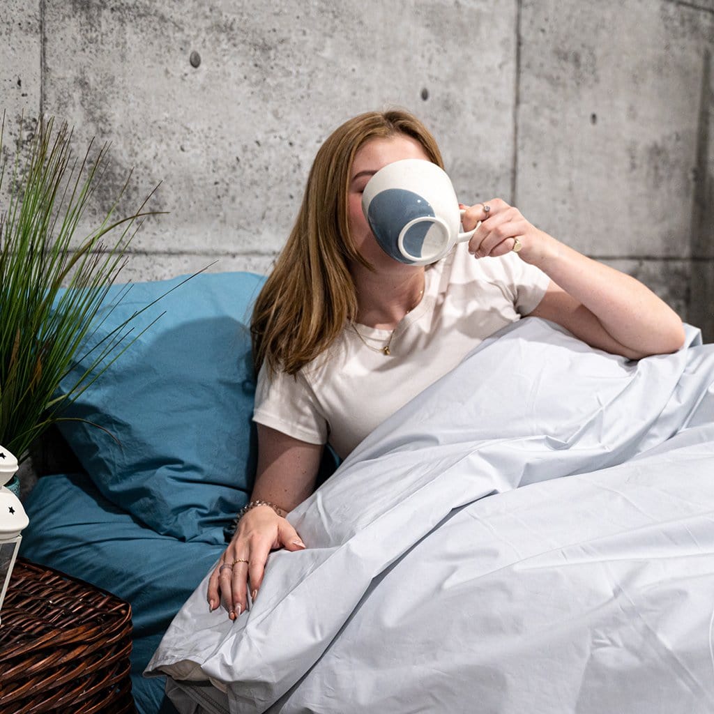 Woman Drinking Coffee in Bed Featuring White Washed Percale Duvet Cover